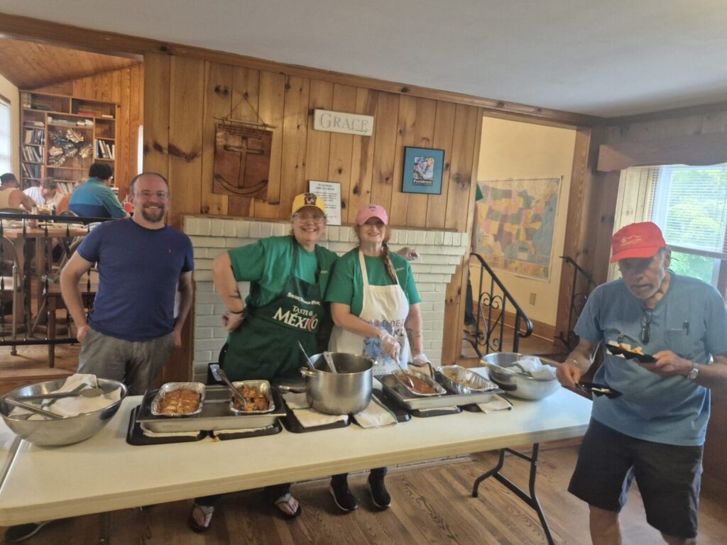 Flourish volunteers smiling behind a table of food as they serve a shared meal