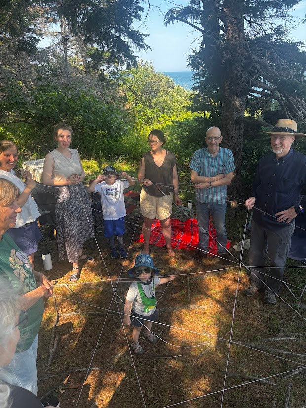 Adults and children gathered in a circle outdoors among trees for Wild Church